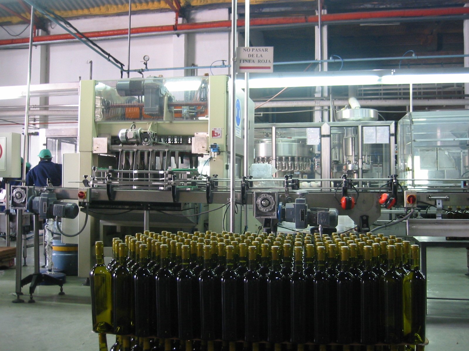 Automated bottling line inside a production plant, with empty glass bottles staged for filling