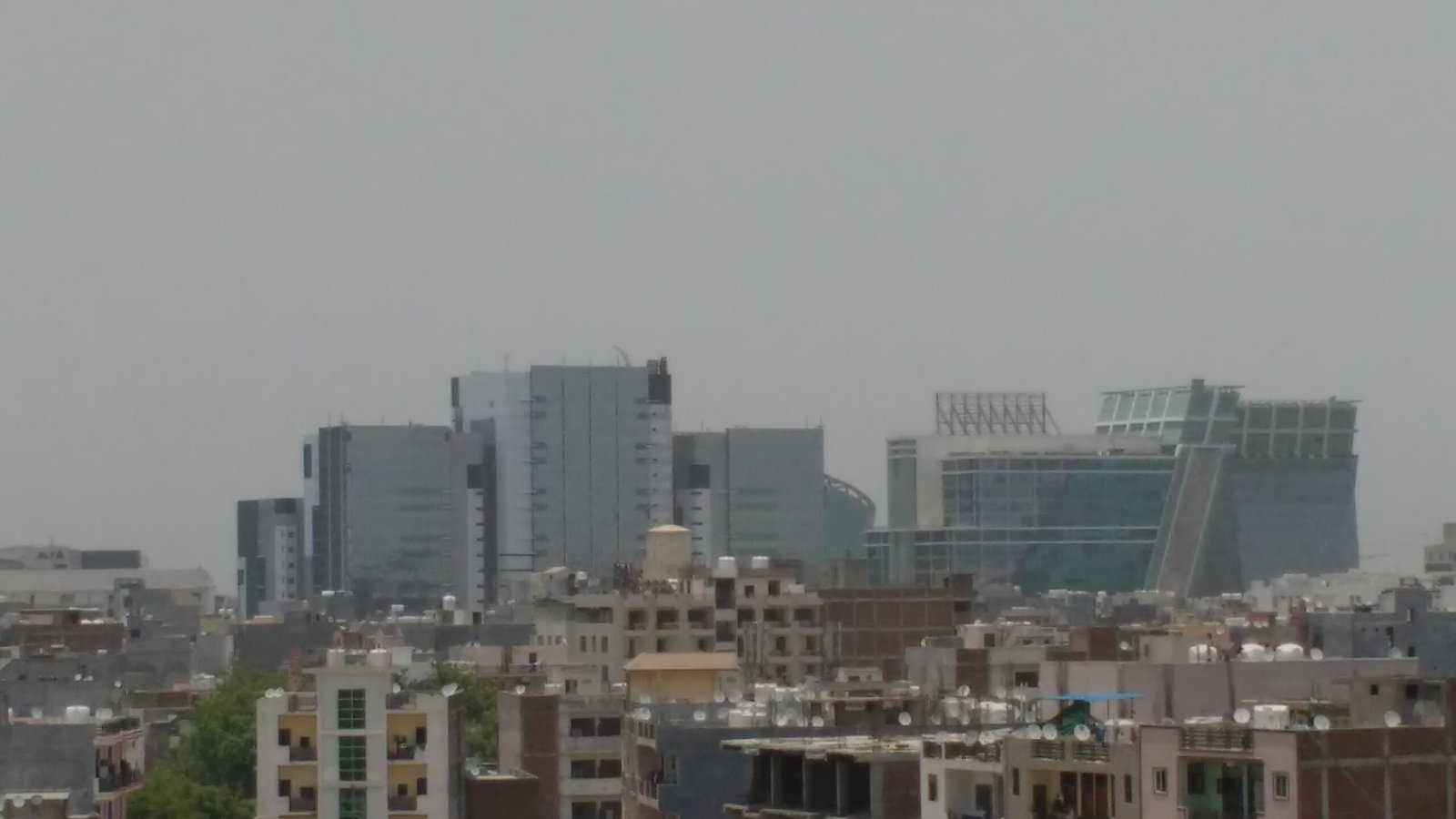 Modern corporate office towers in Gurgaon Cyber City rising above dense residential rooftops in Delhi NCR