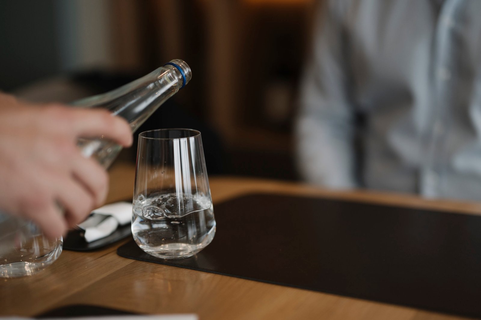 Waiter serving mineral water in a glass at a hotel restaurant table